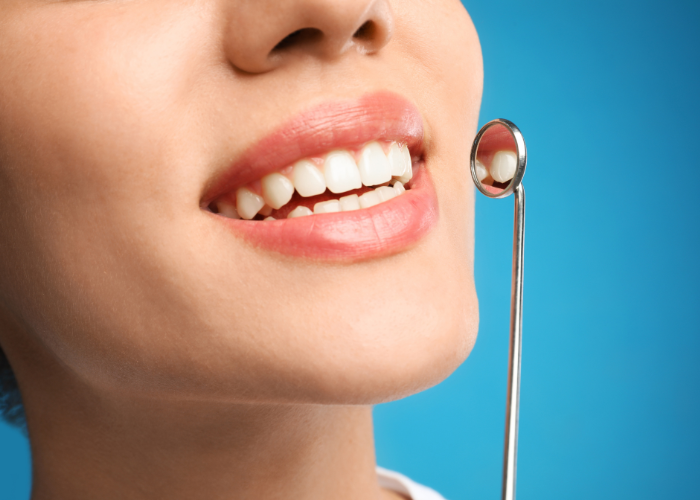 Smiling woman showcasing healthy teeth with dental mirror, emphasizing cosmetic dentistry and oral health care.