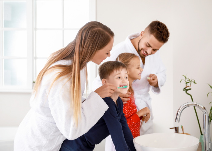 Family brushing teeth together in a bathroom, promoting healthy oral hygiene habits for children and adults.