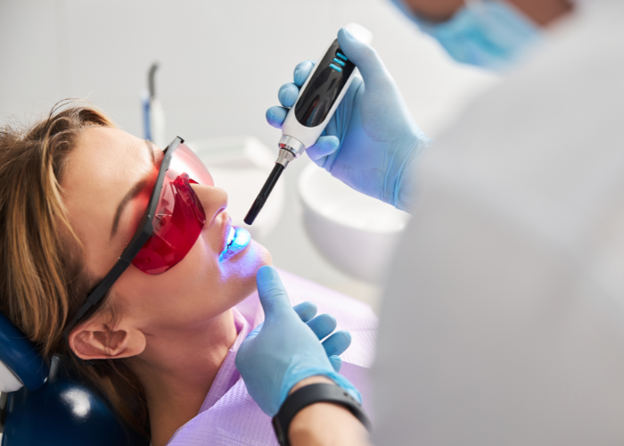 Woman receiving dental treatment with a dental curing light in a modern clinic, wearing protective eyewear and seated in a dental chair, emphasizing preventive care for oral health.