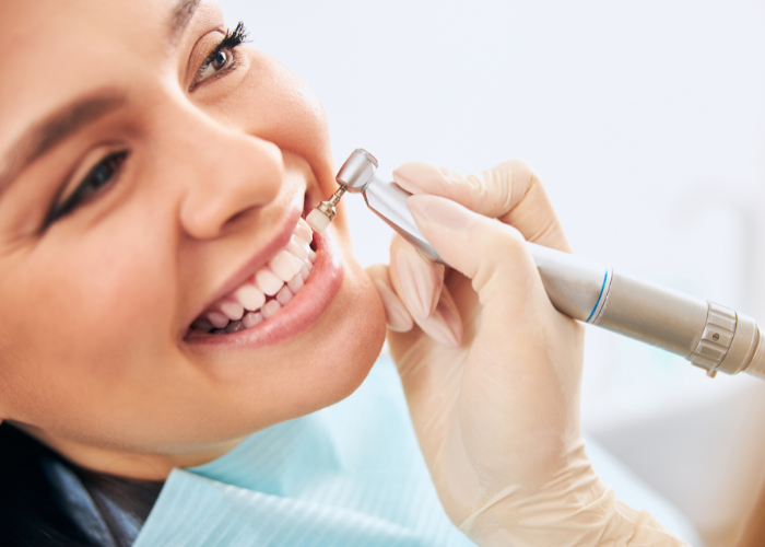 Dental hygienist performing teeth cleaning on a smiling patient, showcasing oral health care techniques.